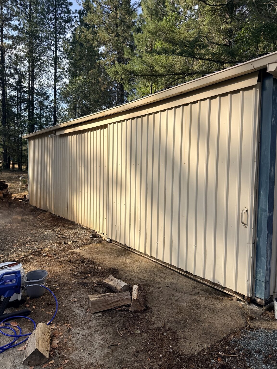 Metal building wall before repaint with sprayer staged